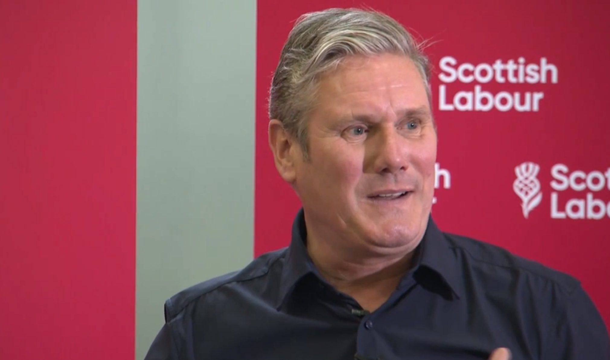 Keir Starmer sitting in front of a Scottish Labour background