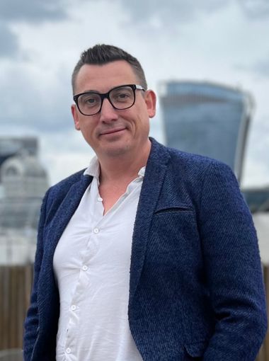 Gavin Shuker, Partner, headshot standing on a London rooftop.