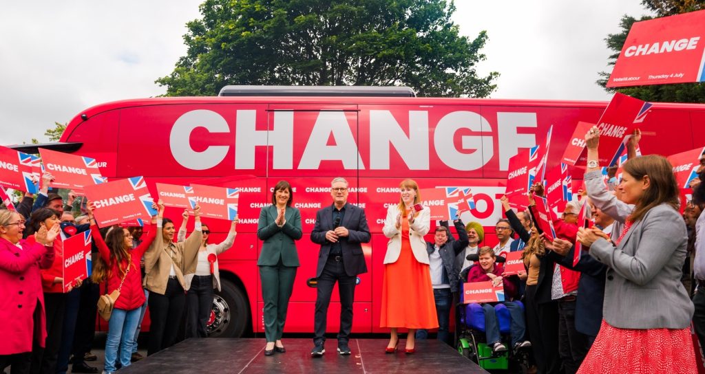 Keir Starmer in front of a large red "change" bus on the campaign trail.