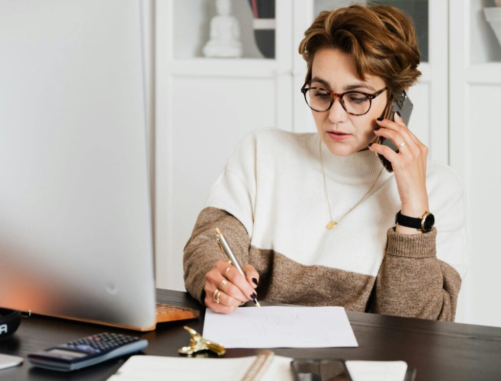 Woman sitting at a desk on the phone.