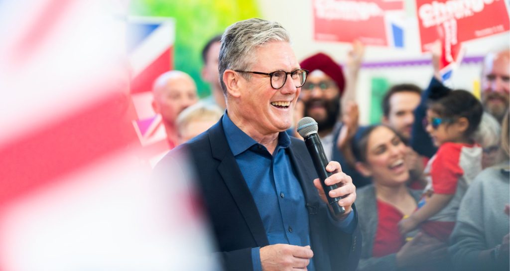 Keir Starmer, leader of the Labour Party, talks into a microhone in front of a crowd.