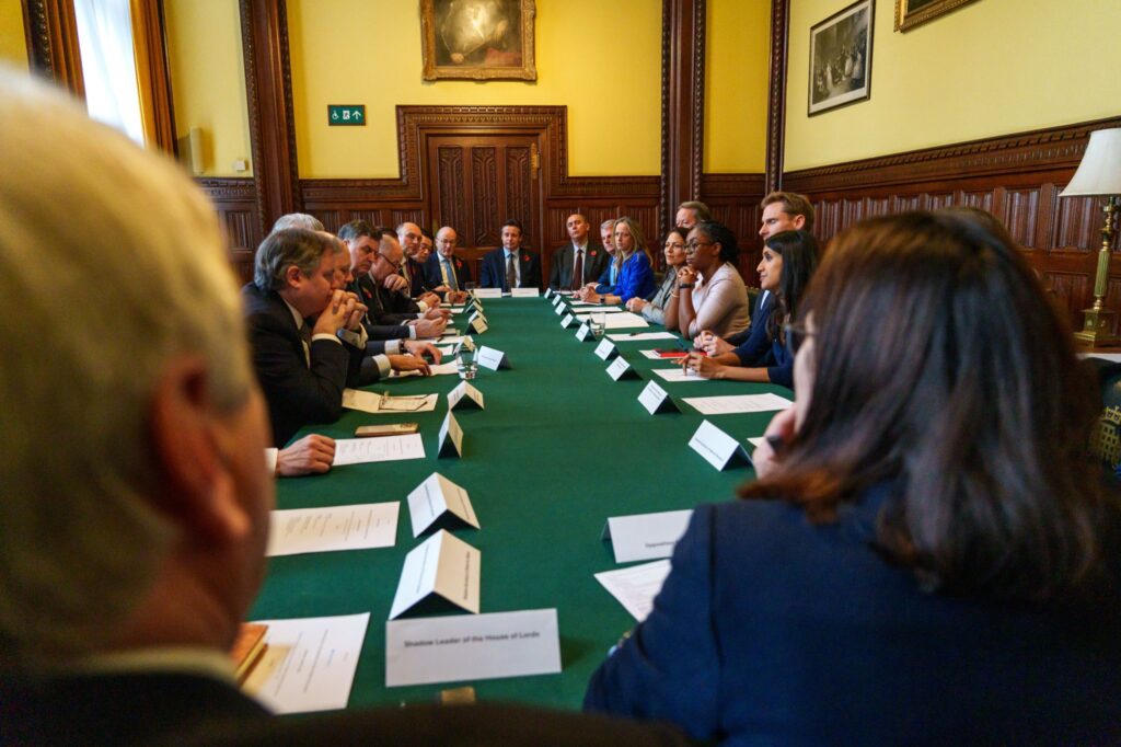 Kemi Badenoch holds her first meeting of the new Shadow Cabinet. Lots of people sit around a long green table in a wood panel room.