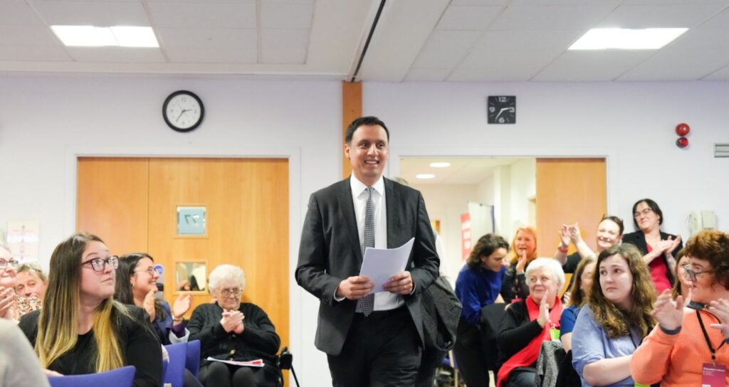 Anas Sarwar smiling as he walks through a room full of people